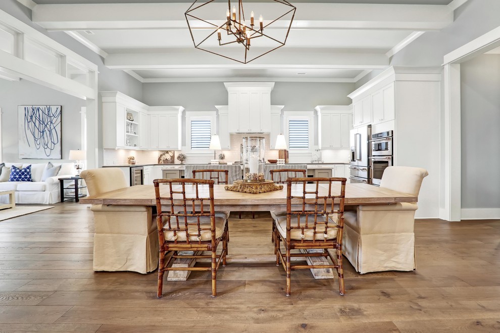 Immagine di una sala da pranzo aperta verso il soggiorno costiera con pareti grigie, pavimento in legno massello medio e pavimento beige