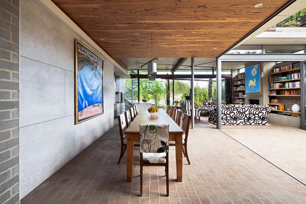 Cette image montre une salle à manger ouverte sur le salon design avec un sol en brique.