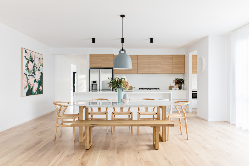 Bild på en minimalistisk matplats med öppen planlösning, med vita väggar, ljust trägolv och beiget golv