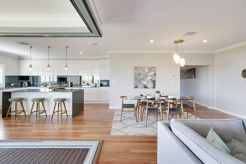 Photo of a large modern open plan dining room in Sydney with beige walls, medium hardwood flooring, a standard fireplace, a metal fireplace surround and brown floors.