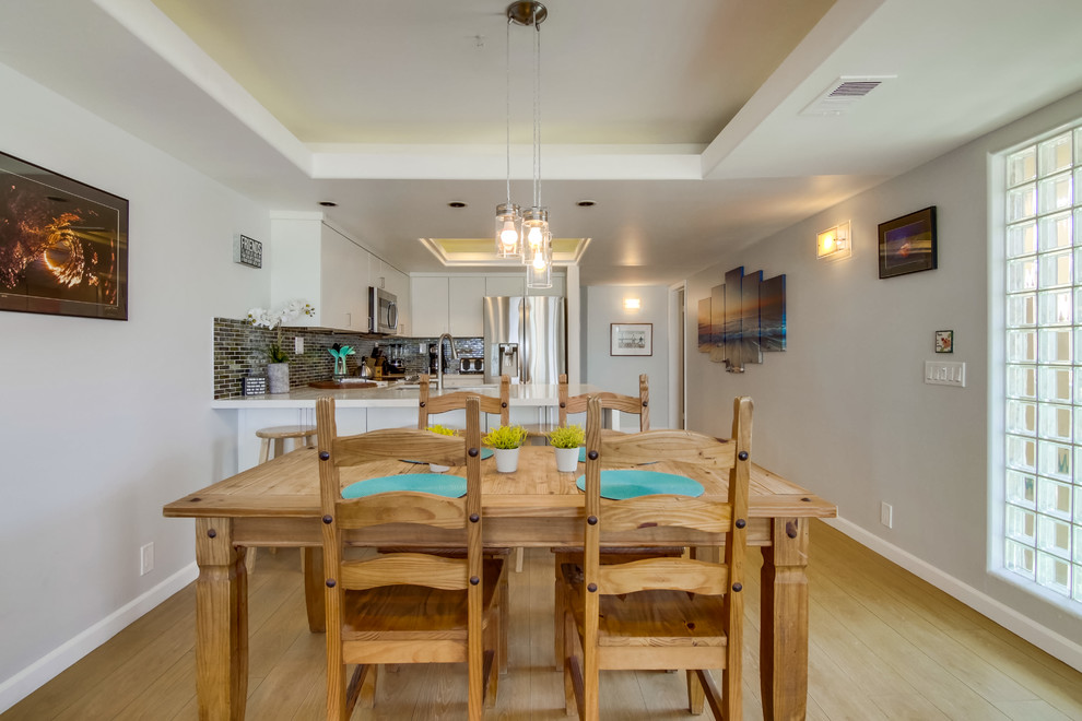 Esempio di una sala da pranzo aperta verso la cucina stile marino con pareti grigie, parquet chiaro e pavimento beige