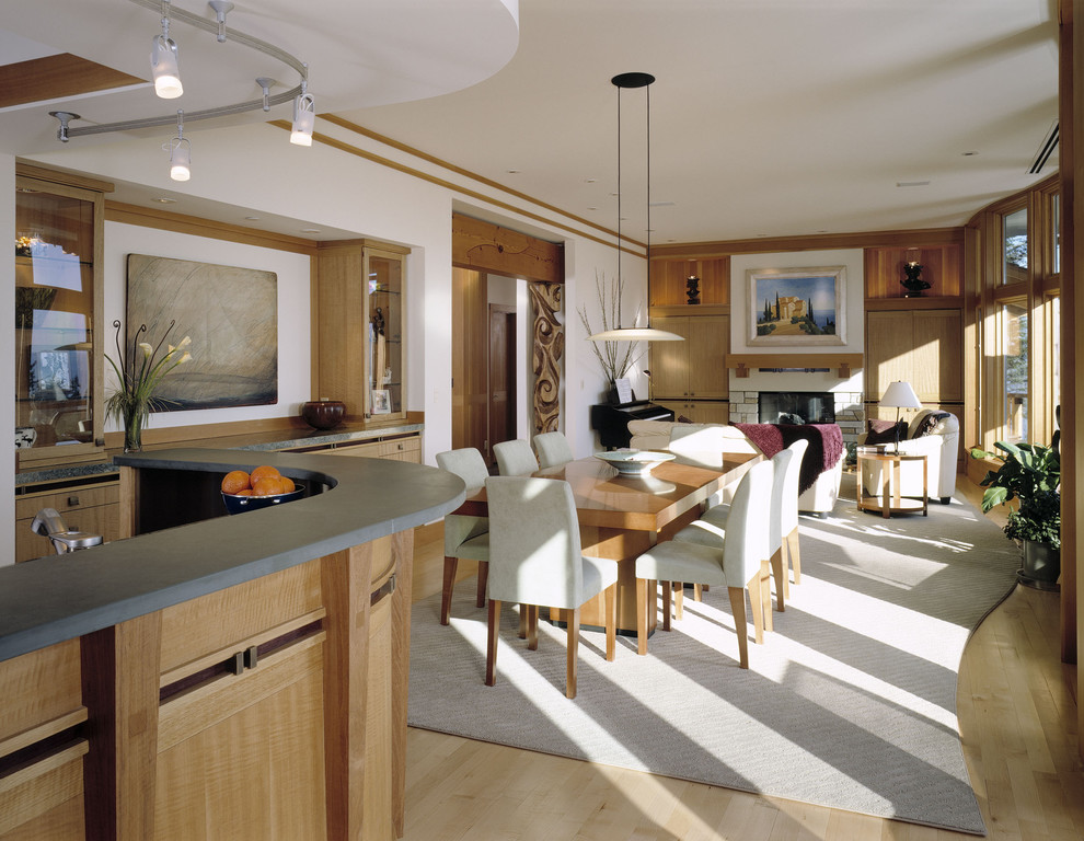 Exemple d'une salle à manger ouverte sur le salon tendance de taille moyenne avec un mur blanc, parquet clair, une cheminée standard, un manteau de cheminée en pierre et un sol beige.