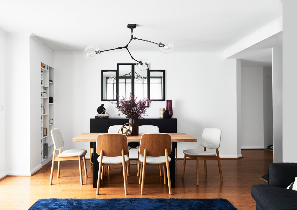 Idées déco pour une salle à manger ouverte sur le salon contemporaine de taille moyenne avec un mur blanc, sol en stratifié, aucune cheminée et un sol marron.