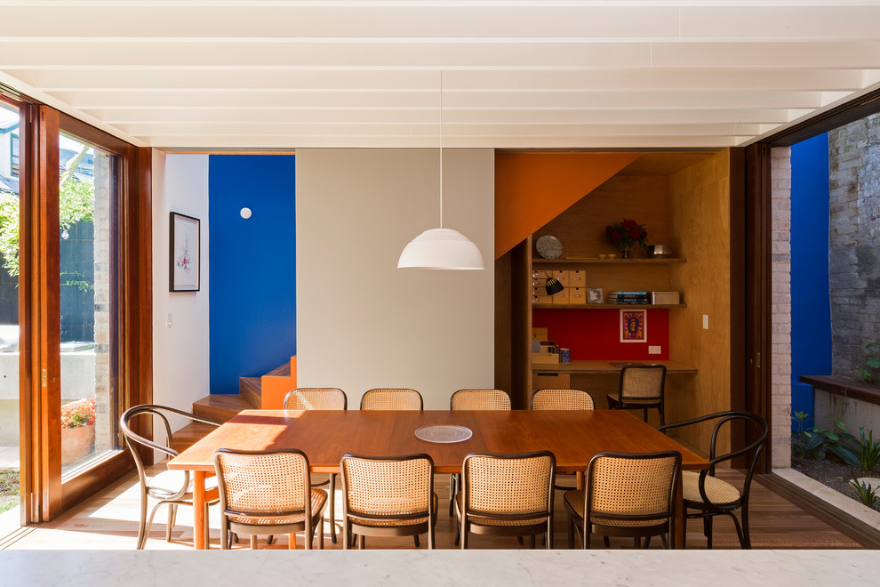 Idées déco pour une salle à manger ouverte sur la cuisine contemporaine de taille moyenne avec un mur multicolore et un sol en bois brun.
