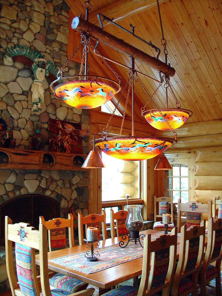 Inspiration pour une salle à manger ouverte sur le salon sud-ouest américain de taille moyenne avec un mur multicolore, parquet clair, une cheminée standard et un manteau de cheminée en pierre.