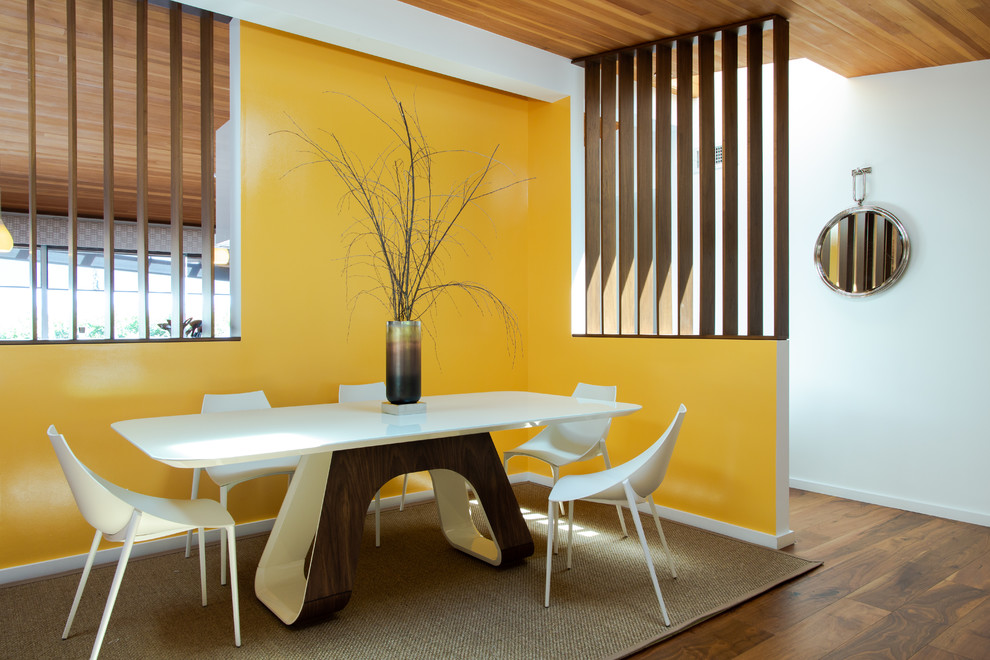 Exemple d'une salle à manger rétro avec un mur jaune, un sol marron et un sol en bois brun.