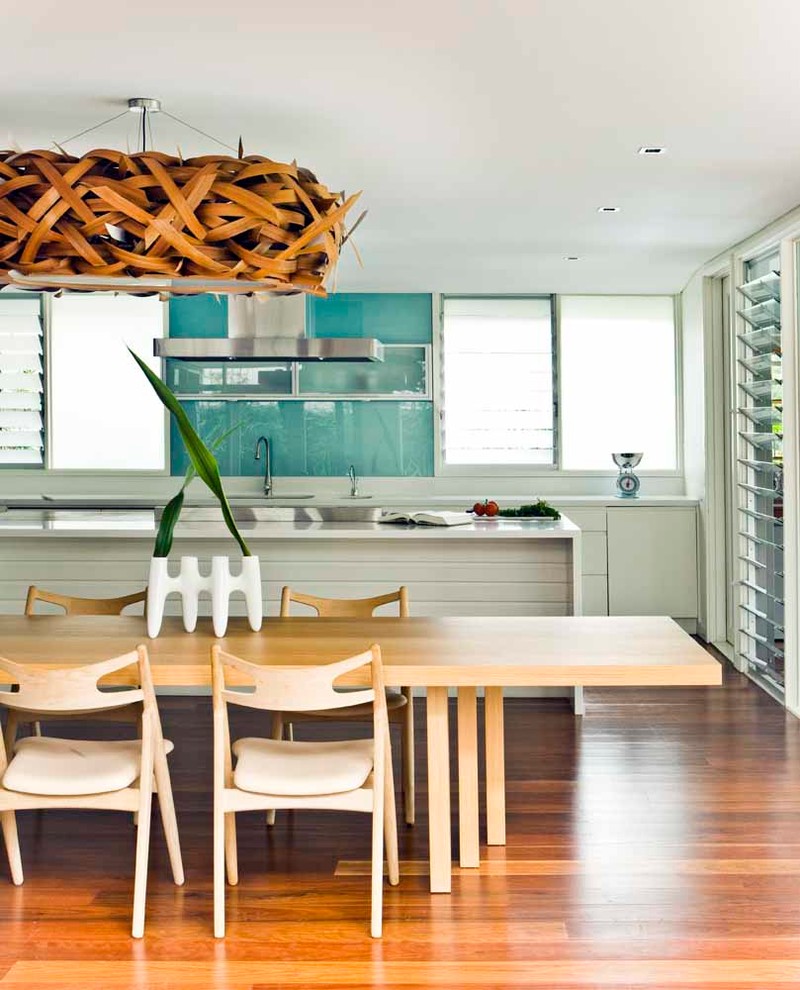 Diseño de comedor de cocina costero sin chimenea con paredes blancas y suelo de madera en tonos medios