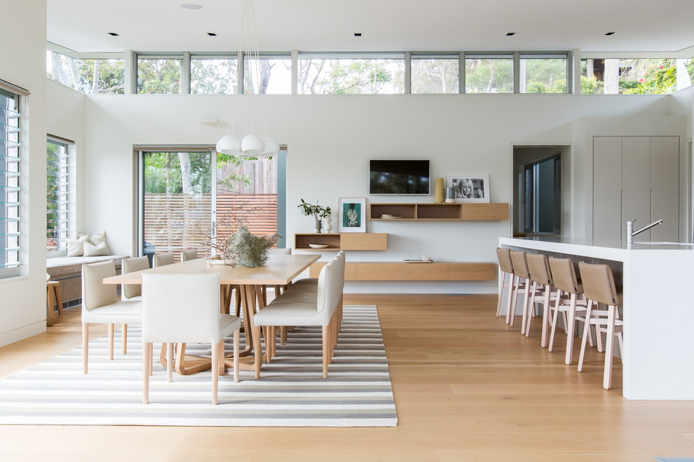 Immagine di una sala da pranzo aperta verso il soggiorno contemporanea con pareti bianche, parquet chiaro e pavimento marrone