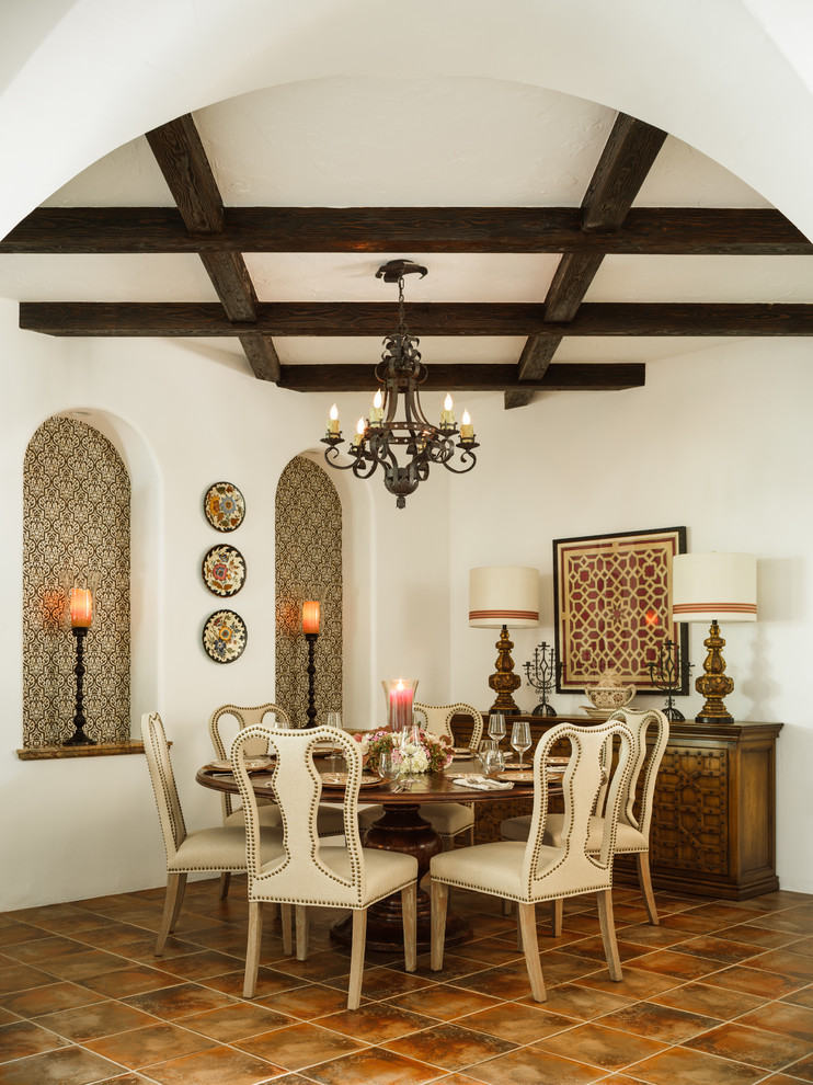 Photo of a mediterranean enclosed dining room in Los Angeles with white walls, brown floors and feature lighting.