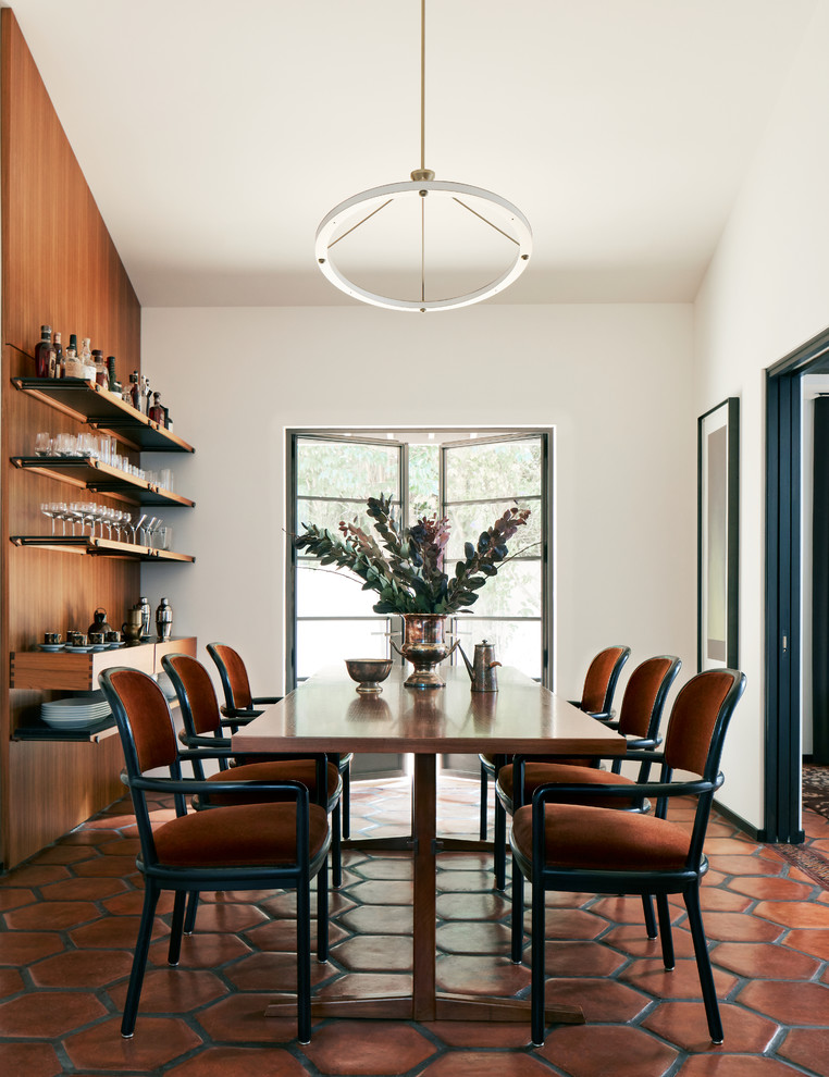 Midcentury dining room in San Francisco with white walls, terracotta flooring and red floors.