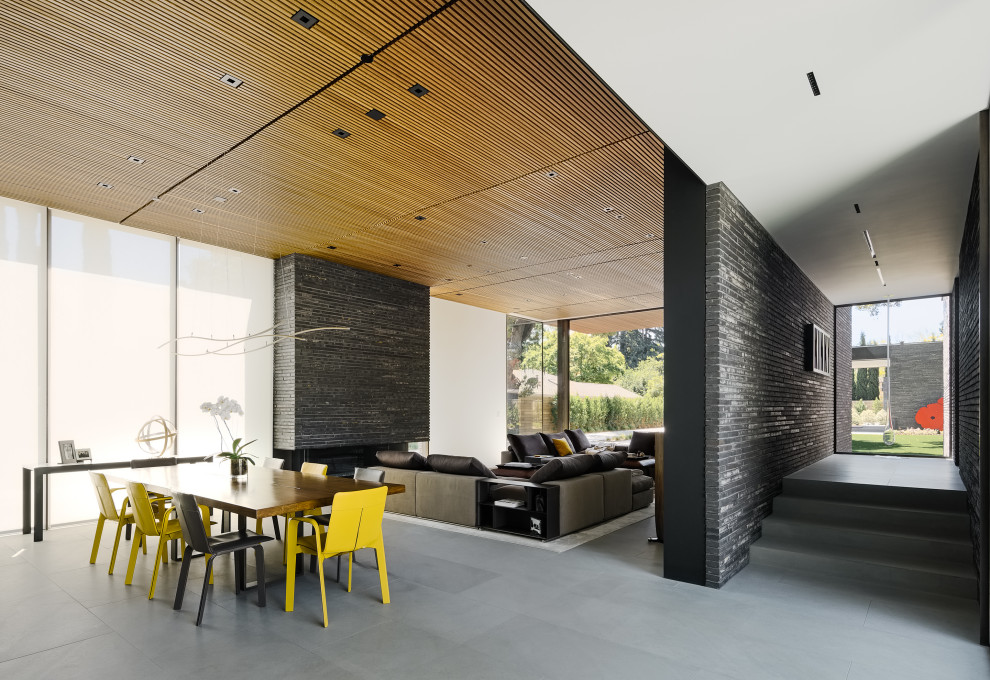 Foto di una sala da pranzo aperta verso il soggiorno moderna con pareti bianche, pavimento grigio e soffitto in legno