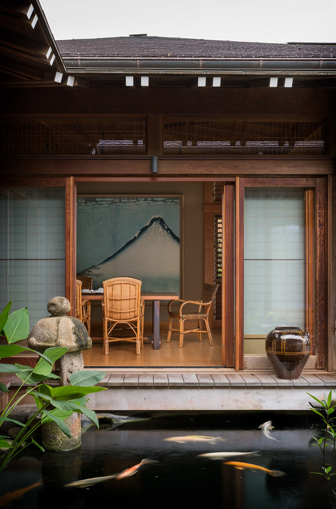 Geschlossenes, Großes Asiatisches Esszimmer ohne Kamin mit beiger Wandfarbe, braunem Holzboden und braunem Boden in Hawaii