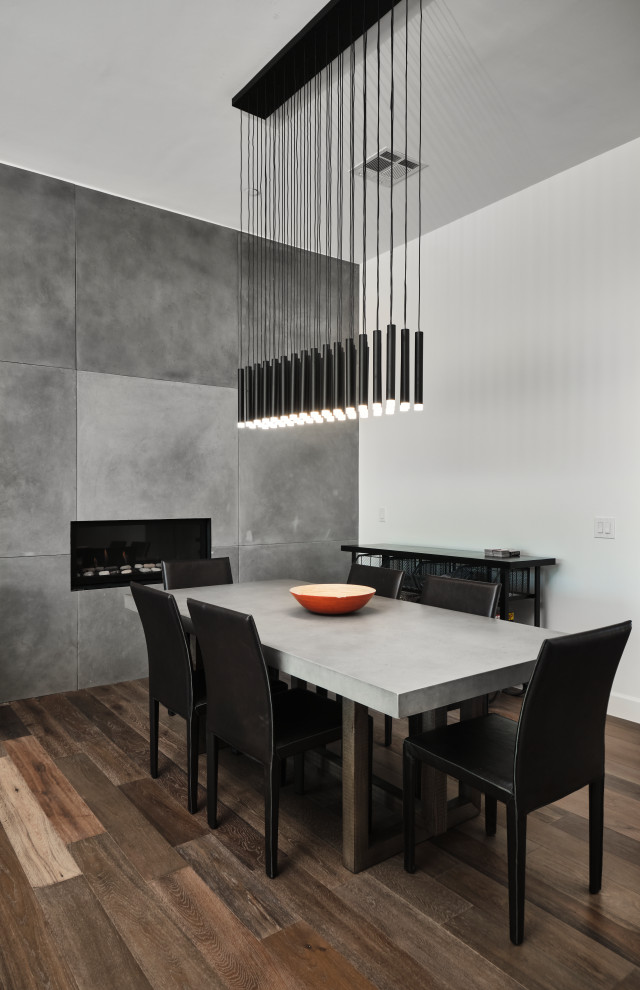 Idées déco pour une salle à manger contemporaine de taille moyenne avec un mur gris, parquet clair, une cheminée standard, un manteau de cheminée en carrelage et un sol marron.