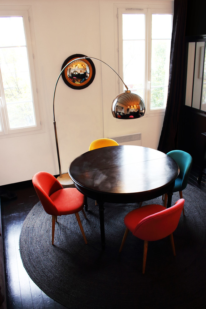 Cette photo montre une petite salle à manger éclectique avec un mur blanc, parquet foncé, aucune cheminée et un sol noir.