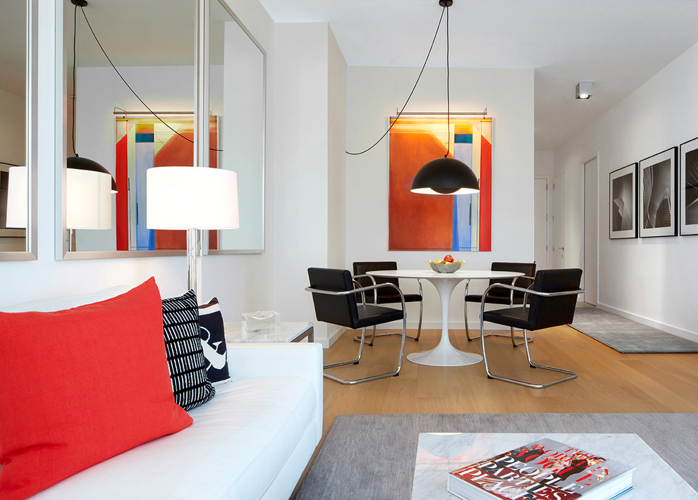 Cette photo montre une petite salle à manger moderne avec un mur blanc, parquet clair et éclairage.