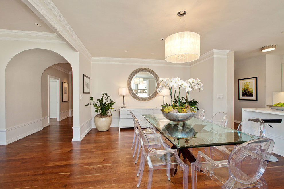 Aménagement d'une salle à manger ouverte sur le salon classique avec un mur beige, parquet foncé et éclairage.