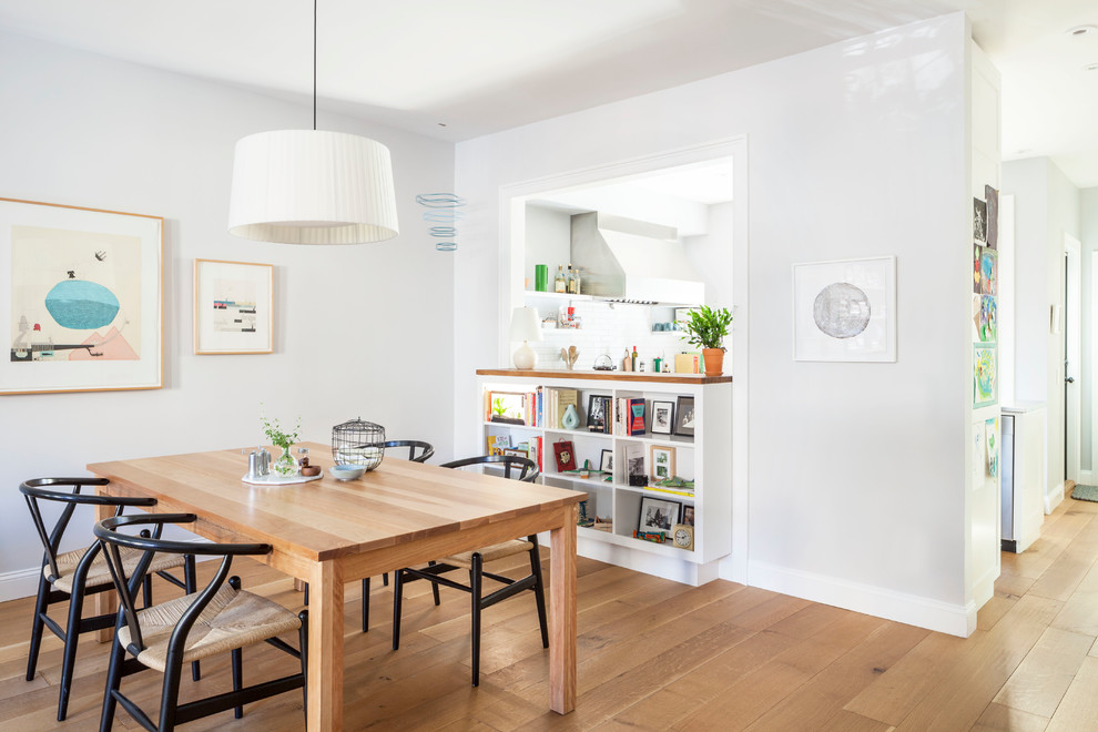 This is an example of a classic dining room in New York with white walls and medium hardwood flooring.