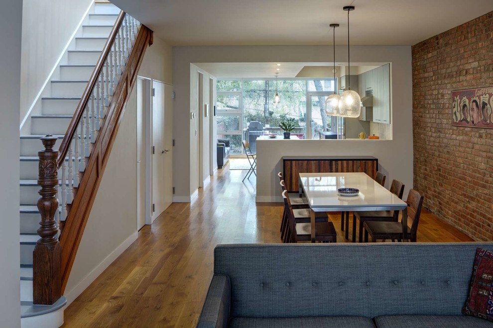 Immagine di una sala da pranzo aperta verso la cucina minimalista con pavimento in legno massello medio e nessun camino