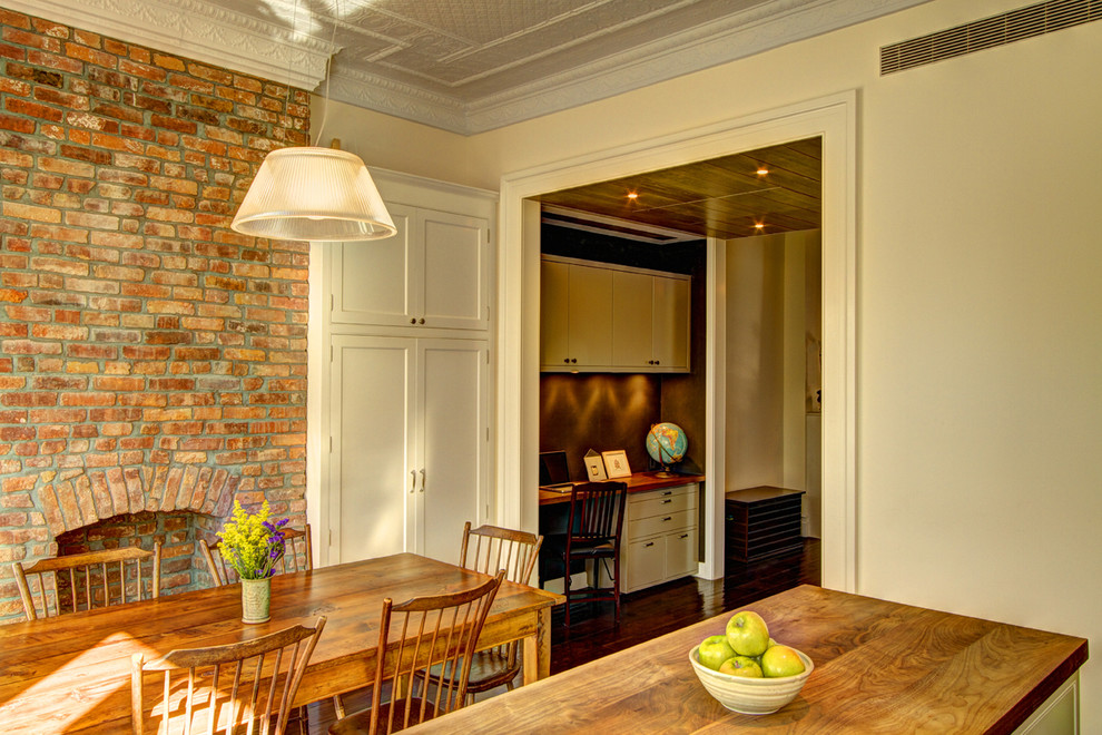 Cette image montre une salle à manger traditionnelle avec un mur beige et un manteau de cheminée en brique.