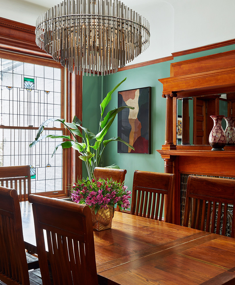Cette image montre une salle à manger traditionnelle fermée et de taille moyenne avec un mur vert, une cheminée standard et un manteau de cheminée en carrelage.