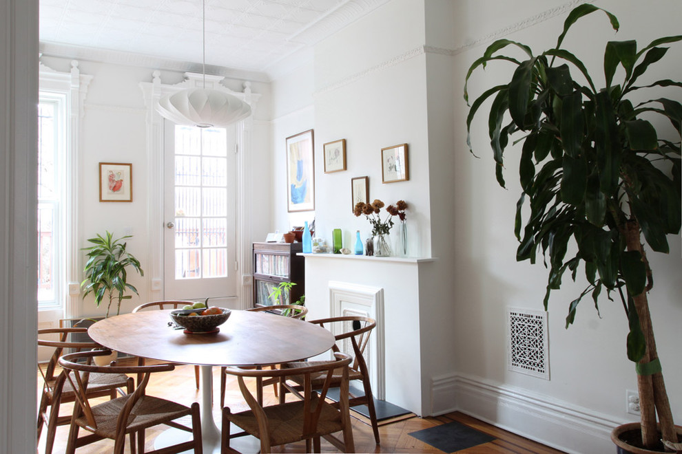 Aménagement d'une salle à manger contemporaine avec un mur blanc et un sol en bois brun.