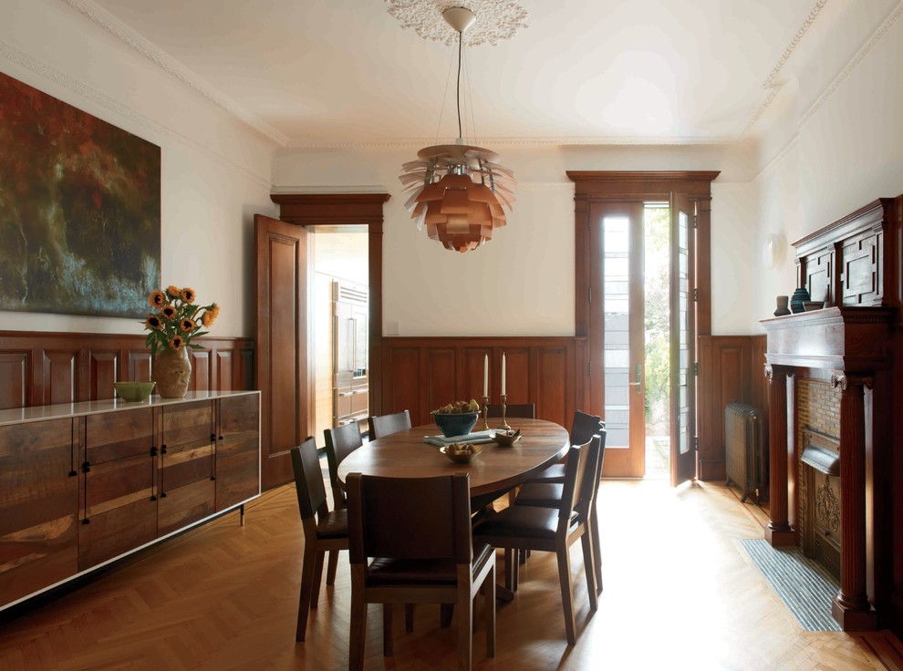 Photo of a contemporary dining room in New York with white walls, medium hardwood flooring, a standard fireplace and a tiled fireplace surround.