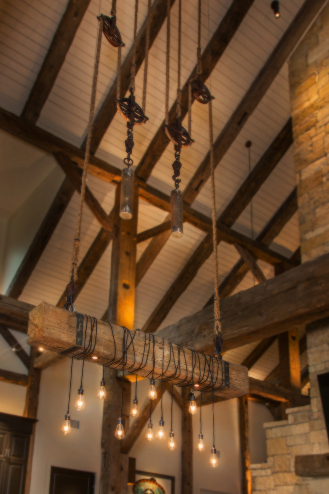 Idée de décoration pour une grande salle à manger ouverte sur le salon chalet avec un mur blanc, un sol en bois brun, une cheminée double-face, un manteau de cheminée en pierre et un sol marron.