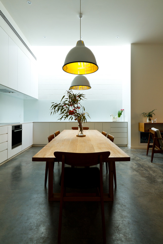 На фото: кухня-столовая среднего размера в современном стиле с белыми стенами и бетонным полом без камина