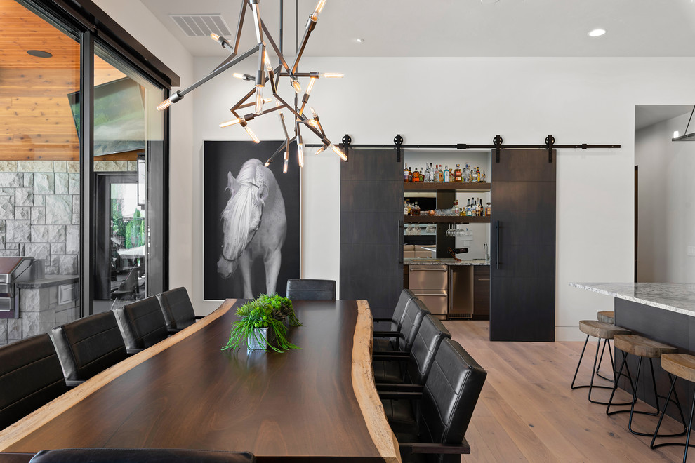 Esempio di una sala da pranzo aperta verso la cucina design con pareti bianche e parquet chiaro