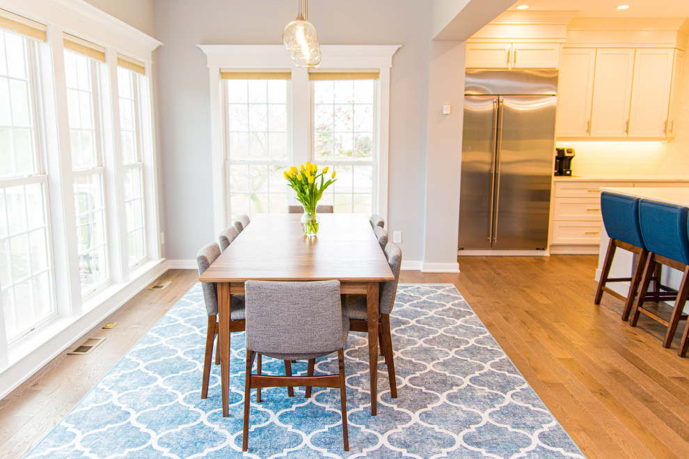 Cette image montre une grande salle à manger ouverte sur la cuisine minimaliste avec un mur gris, parquet clair et un sol multicolore.