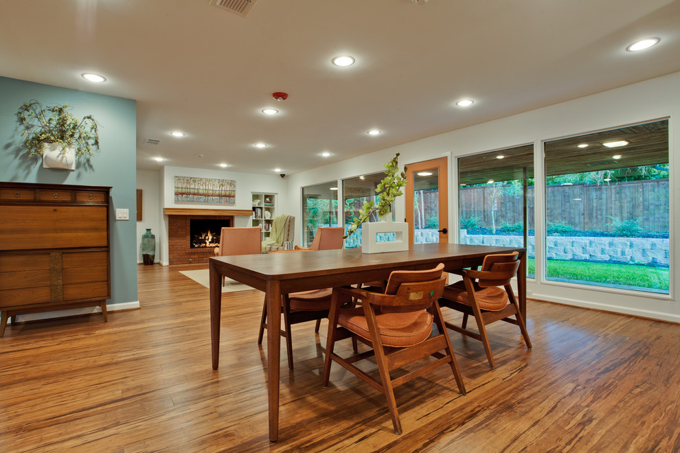 Источник вдохновения для домашнего уюта: большая гостиная-столовая в стиле ретро с белыми стенами, полом из бамбука, стандартным камином и фасадом камина из кирпича