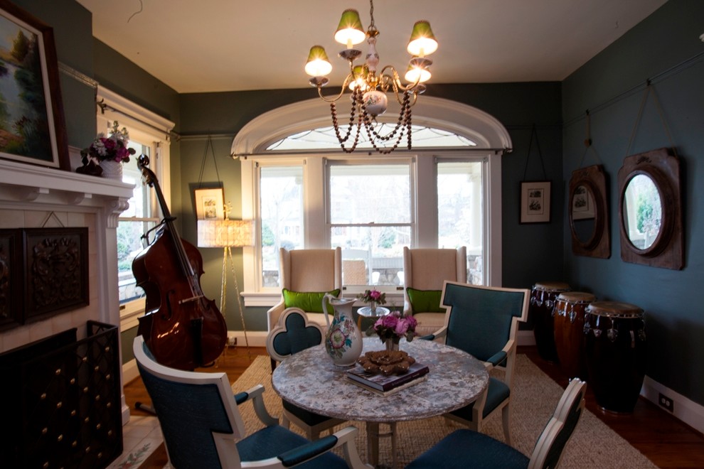 Idée de décoration pour une salle à manger ouverte sur le salon design de taille moyenne avec un mur vert, un sol en bois brun, une cheminée standard et un manteau de cheminée en béton.