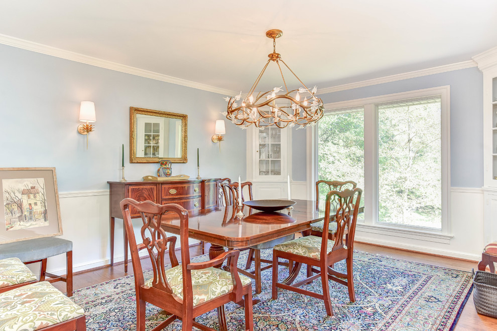 Medium sized modern enclosed dining room with blue walls, medium hardwood flooring, a standard fireplace, a brick fireplace surround and brown floors.