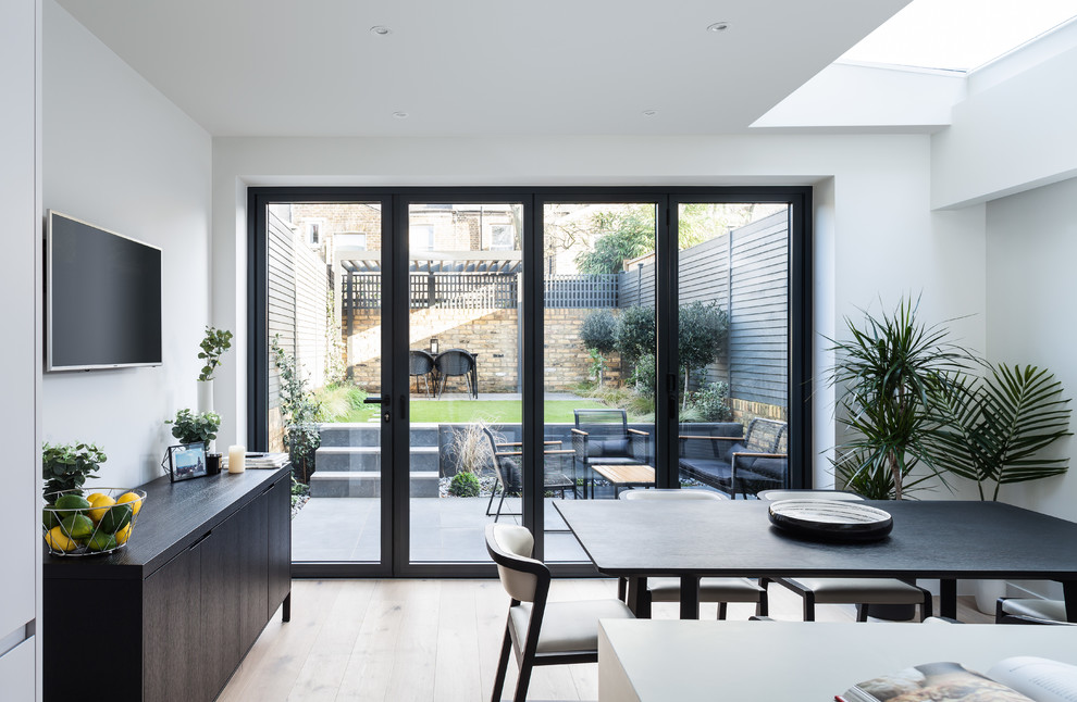 Large contemporary kitchen/dining room in London with white walls, light hardwood flooring and no fireplace.