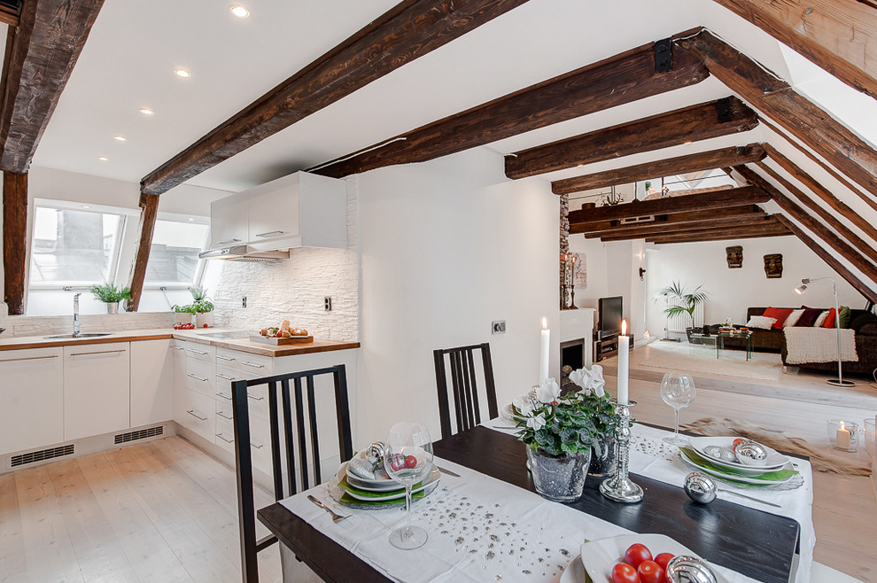 На фото: огромная кухня-столовая в скандинавском стиле с белыми стенами и светлым паркетным полом без камина