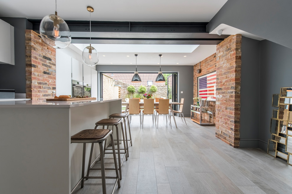 Immagine di una sala da pranzo aperta verso il soggiorno industriale con pareti grigie e pavimento con piastrelle in ceramica