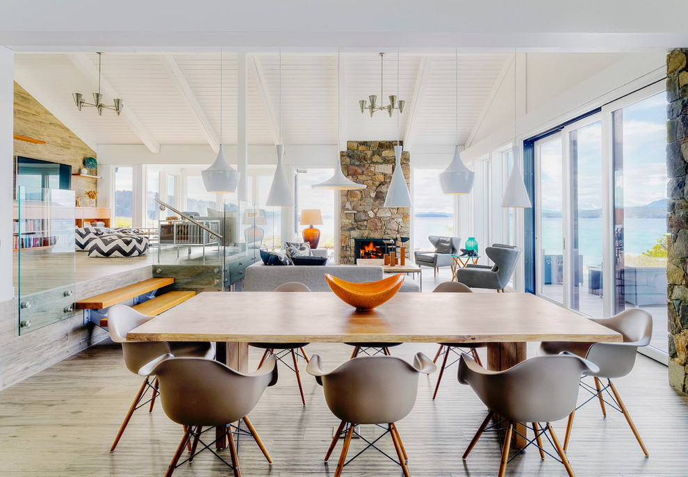 Cette image montre une salle à manger ouverte sur le salon marine avec un mur blanc, parquet clair et éclairage.