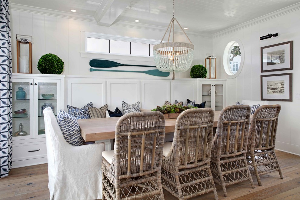 Example of a beach style medium tone wood floor dining room design in Orange County with white walls