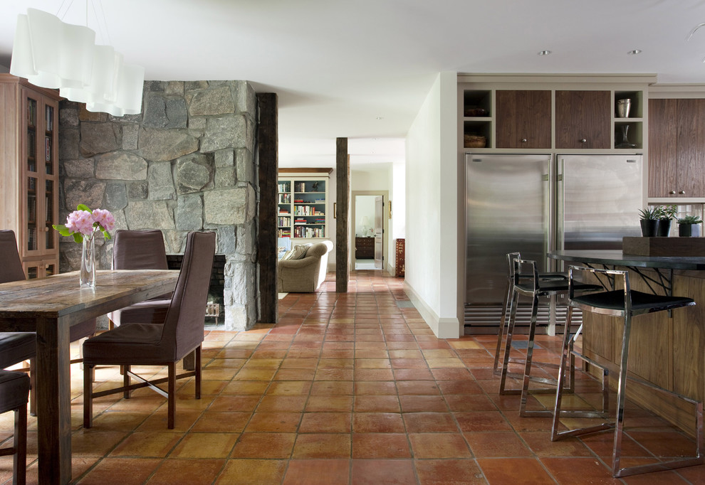 Ispirazione per una sala da pranzo stile rurale con cornice del camino in pietra e pavimento in terracotta