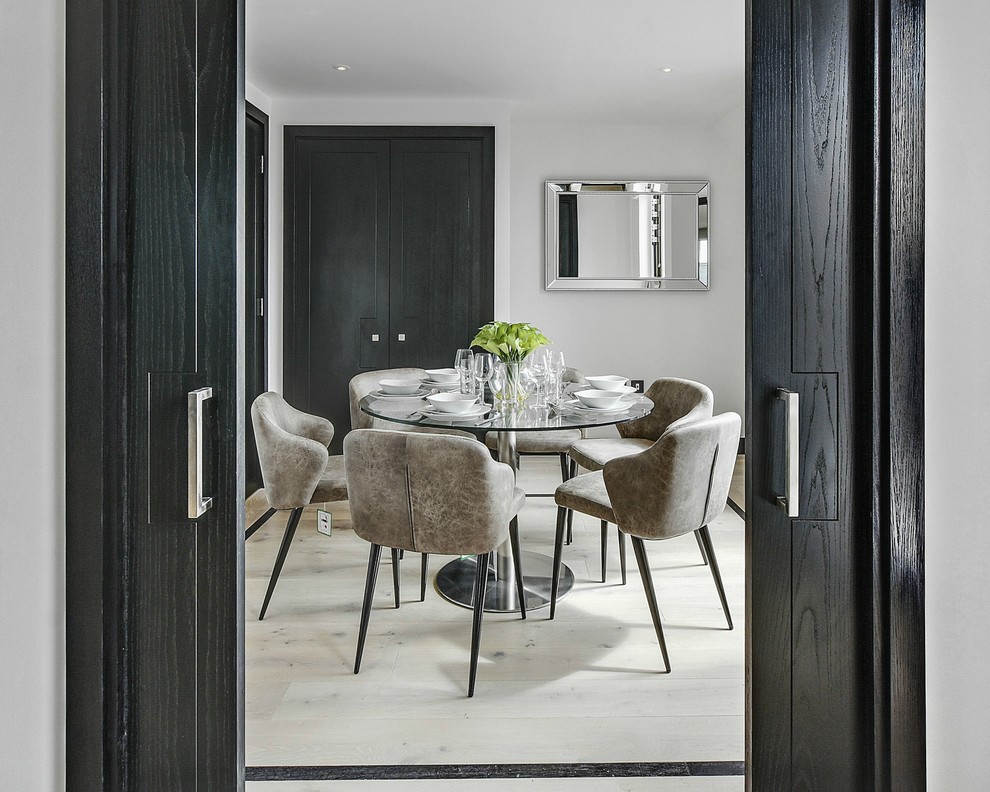 This is an example of a small contemporary open plan dining room in London with white walls, light hardwood flooring and no fireplace.