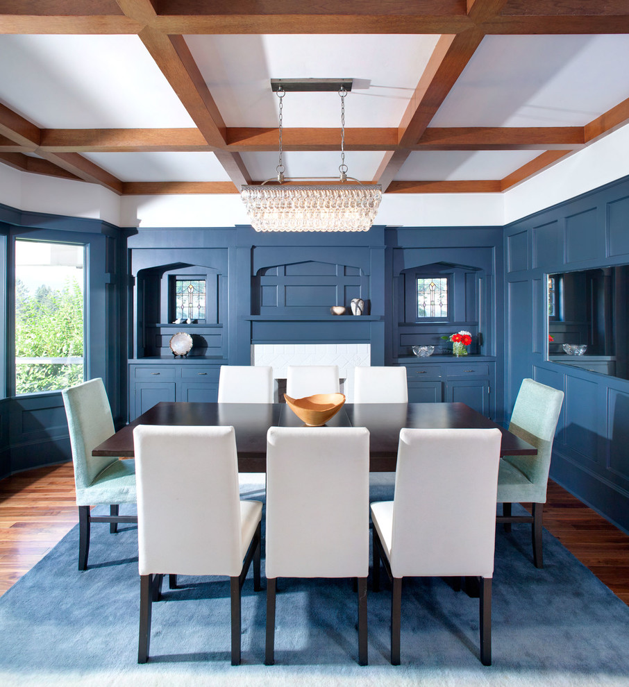 Foto di una sala da pranzo american style con pareti blu, pavimento in legno massello medio e camino classico