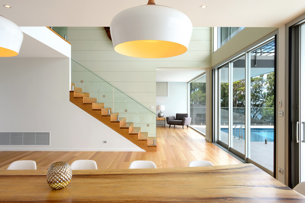 Inspiration pour une salle à manger ouverte sur la cuisine minimaliste de taille moyenne avec un mur blanc et un sol en bois brun.
