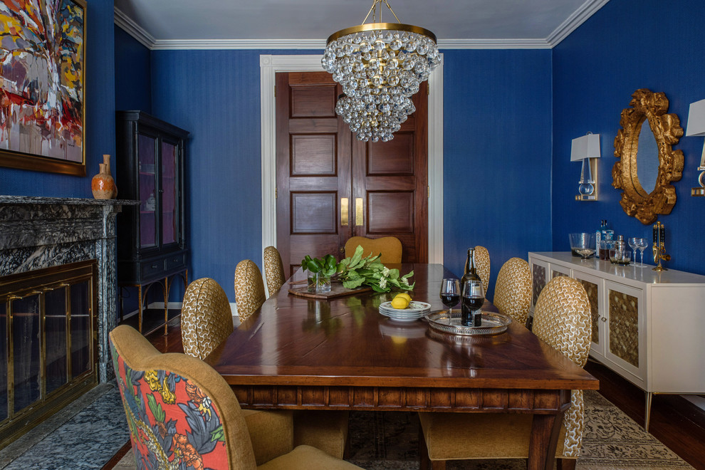 Cette image montre une grande salle à manger traditionnelle avec un mur bleu, parquet foncé, une cheminée standard, un manteau de cheminée en pierre et un sol marron.