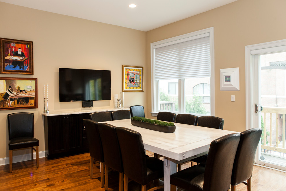 Cette image montre une grande salle à manger ouverte sur la cuisine design avec un mur beige et un sol en bois brun.