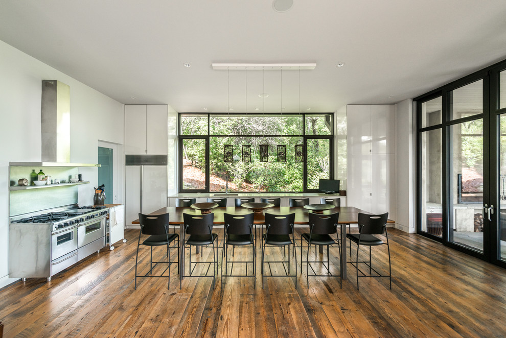 Exemple d'une salle à manger ouverte sur la cuisine tendance avec un mur blanc, un sol en bois brun et un sol marron.
