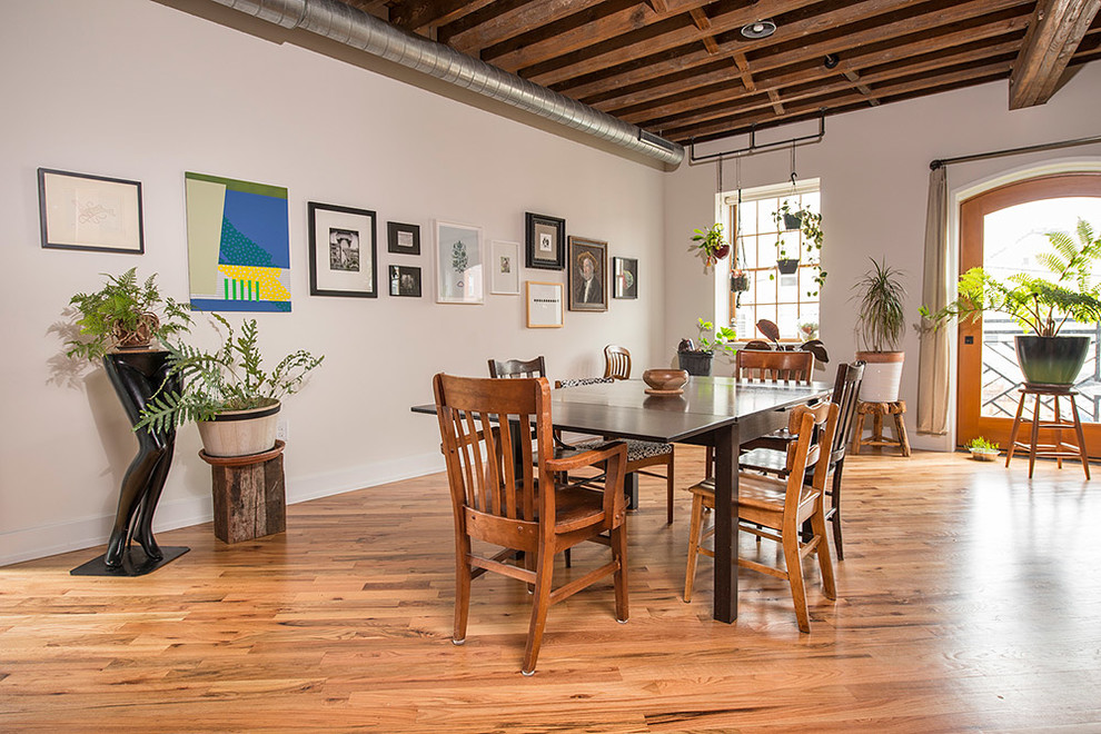 This is an example of an urban dining room in Philadelphia with white walls and medium hardwood flooring.
