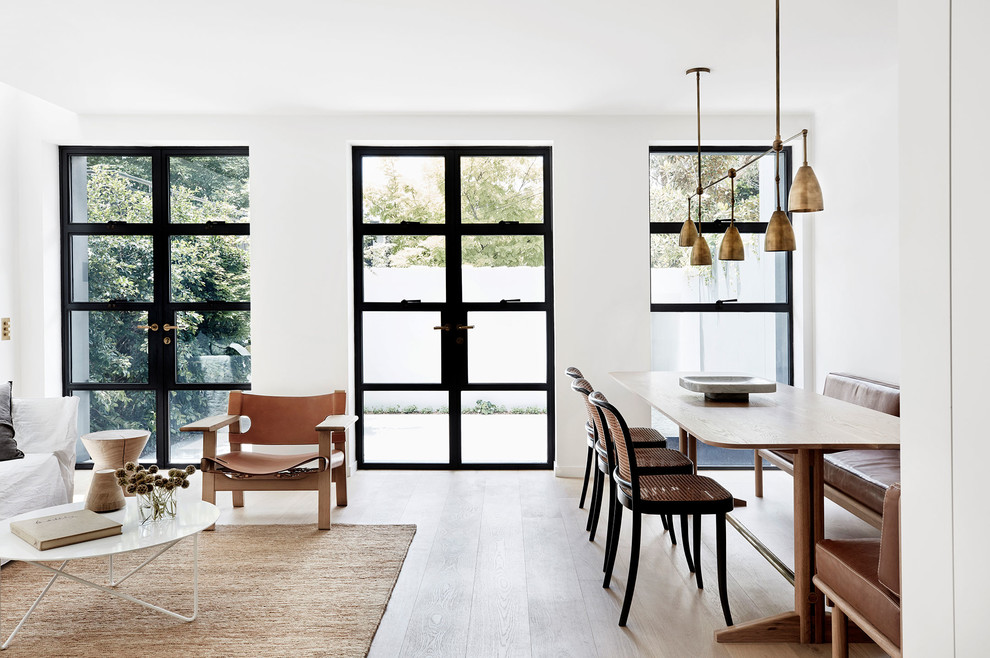 Foto di una sala da pranzo aperta verso il soggiorno nordica con pareti bianche, pavimento in legno massello medio e pavimento marrone