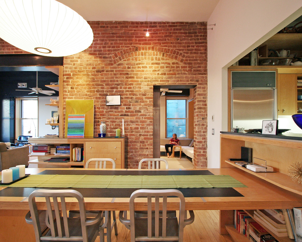 Foto di una sala da pranzo aperta verso il soggiorno industriale con pareti bianche e pavimento in legno massello medio