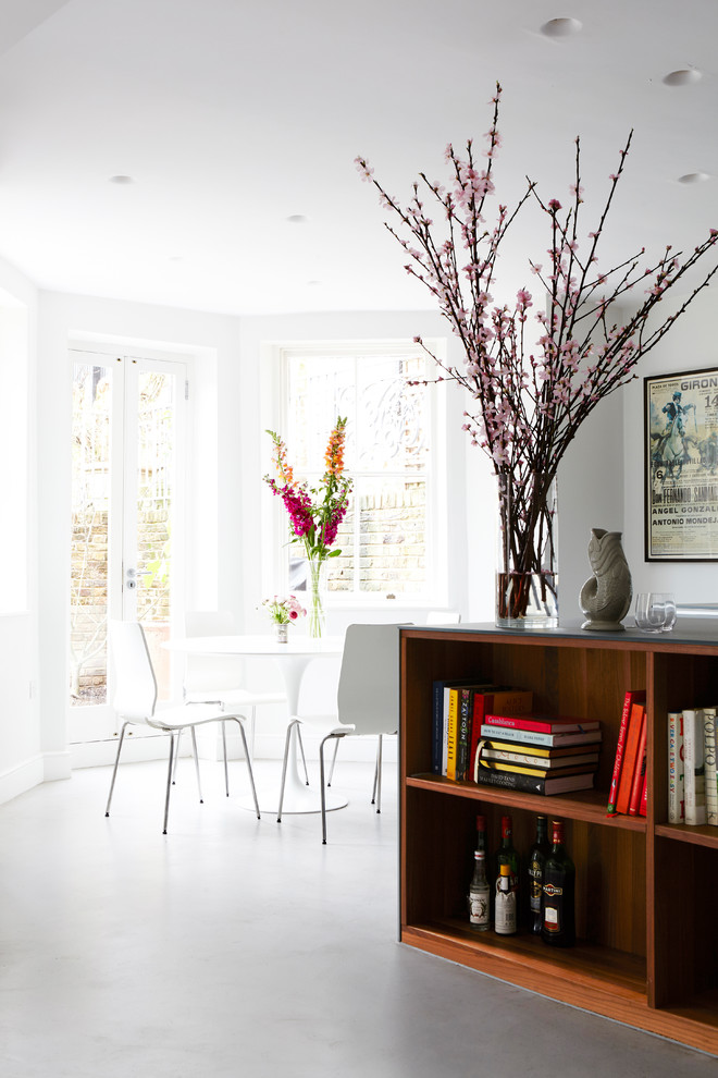 This is an example of a modern kitchen/dining room in London with white walls and white floors.