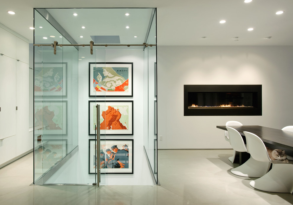 Offenes Modernes Esszimmer mit weißer Wandfarbe, Gaskamin, Betonboden und Kaminumrandung aus Metall in Seattle